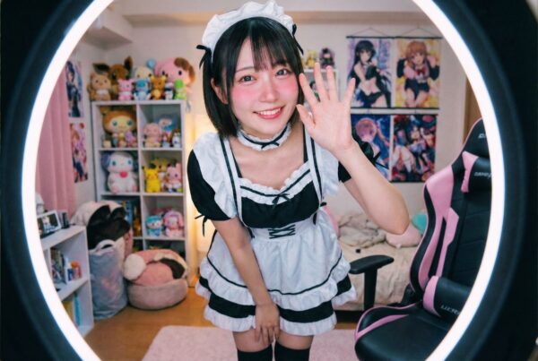 ウェブカメラ越しに笑顔で手を振る、メイド服姿のライブチャット女性